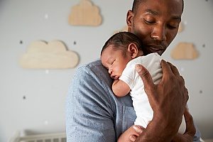 a man holding his newborn son and taking his granted FMLA leave