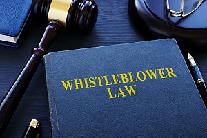 blue whistleblower law book with a brown judge gavel on a table