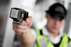 view of a loaded stun gun in a hand of a young man wearing high visibility vest