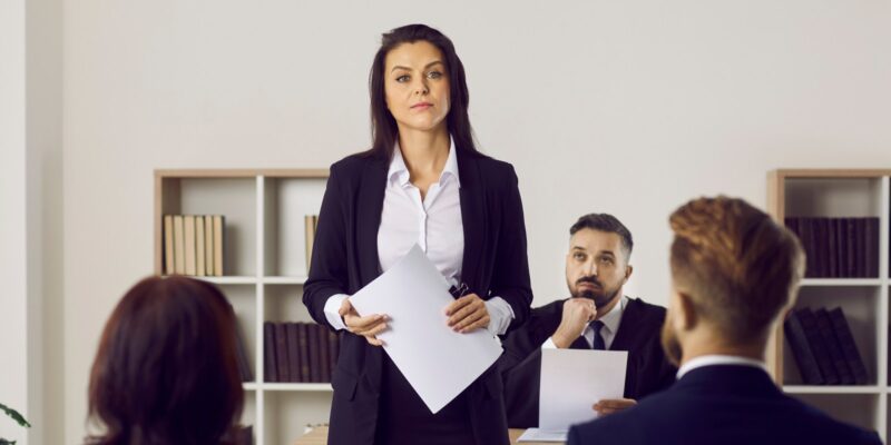 A female attorney holding a false arrest lawsuit while her colleagues starring at her