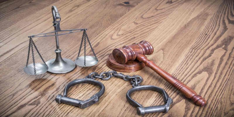 Judge gavel, old handcuffs, and weight scale of justice